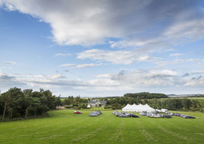 New Century Tent wedding marquee hire in field surrounded by guests cars