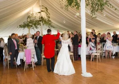 the bride and groom arrive into the wedding marquee hire and the guests are waiting to welcome them