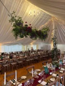 Stylish winter marquee wedding reception with dance floor, floral decorations, and string lights.